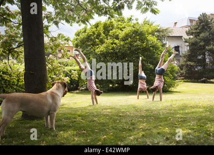 Plusieurs de composite young woman doing handstands in garden Banque D'Images