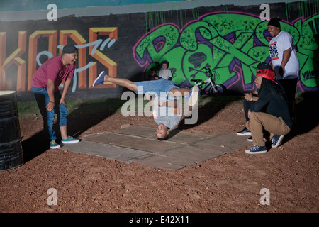 Groupe d'hommes et garçons breakdancing en parc de nuit Banque D'Images