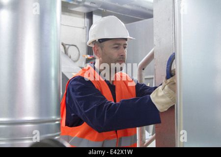 Un technicien vérifier pour tuyaux dans power station Banque D'Images