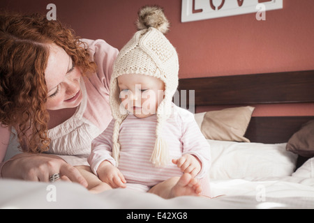 Portrait of mid adult mother and baby girl en étoffes hat