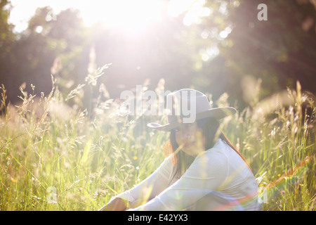 Portrait de femme mature dans la longue herbe wearing cowboy hat Banque D'Images