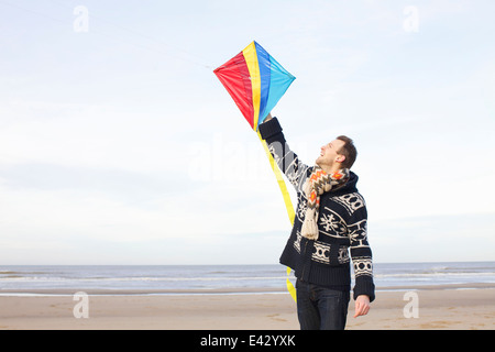 Mid adult man holding up kite sur plage, Bloemendaal aan Zee, Pays-Bas Banque D'Images