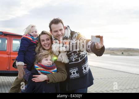 Mid adult man de prendre une famille en selfies stationnement côtières Banque D'Images