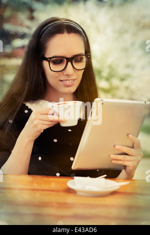 Jeune femme avec des lunettes et tablette Le Café Banque D'Images