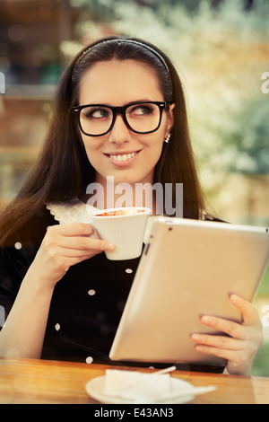 Jeune femme avec des lunettes et tablette Le Café Banque D'Images