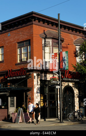 Couple walking passé Marcello restaurant italien et pizzeria sur Commercial à Vancouver, BC, Canada Banque D'Images