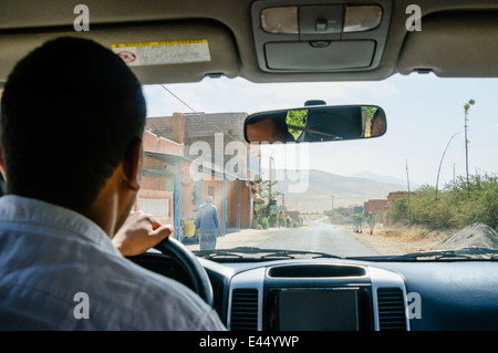 La conduite dans un 4x4 Jeep à travers un village berbère dans les montagnes de l'Atlas, au Maroc. Banque D'Images