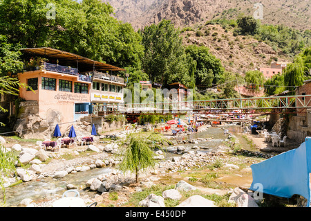 Tables, chaises de patio en plastique avec des parasols dans les restaurants sur les rives de la rivière de l'Ourika, la vallée de l'Ourika, Atlas, Maroc Banque D'Images