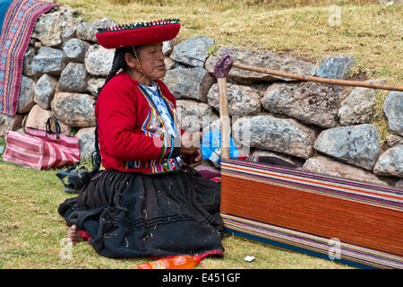 Femme âgée portant un chapeau, les Indiens Quechua dans un costume traditionnel, assis sur le plancher et de travail sur une civière d'un métier Banque D'Images
