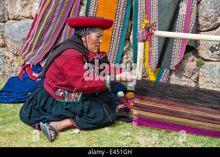 Femme âgée portant un chapeau, en vêtements traditionnels indiens Quechua, assis sur le plancher travaillant sur la civière d'un métier Banque D'Images