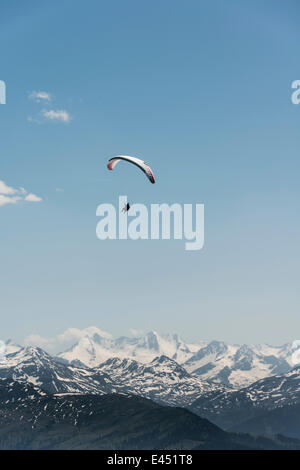 Parapentiste contre un ciel bleu, les sommets enneigés des Alpes à l'arrière Banque D'Images