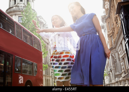 Deux jeunes femmes debout dans London street, forme d'arrêt de bus Banque D'Images