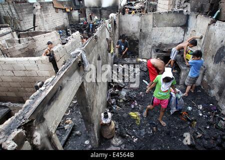 Mandaluyong City, Philippines. 3 juillet, 2014. Résidents comptent pour des matériaux réutilisables après un incendie a frappé une zone résidentielle à Mandaluyong City, Philippines, le 3 juillet 2014. L'incendie a laissé plus de 100 personnes sans-abri et une fille est morte dans l'accident. Credit : Rouelle Umali/Xinhua/Alamy Live News Banque D'Images