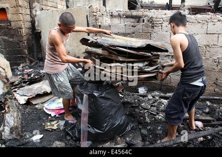 Mandaluyong City, Philippines. 3 juillet, 2014. Résidents comptent pour des matériaux réutilisables après un incendie a frappé une zone résidentielle à Mandaluyong City, Philippines, le 3 juillet 2014. L'incendie a laissé plus de 100 personnes sans-abri et une fille est morte dans l'accident. Credit : Rouelle Umali/Xinhua/Alamy Live News Banque D'Images