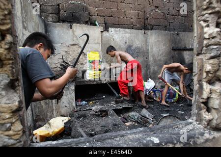 Mandaluyong City, Philippines. 3 juillet, 2014. Résidents comptent pour des matériaux réutilisables après un incendie a frappé une zone résidentielle à Mandaluyong City, Philippines, le 3 juillet 2014. L'incendie a laissé plus de 100 personnes sans-abri et une fille est morte dans l'accident. Credit : Rouelle Umali/Xinhua/Alamy Live News Banque D'Images