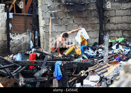 Mandaluyong City, Philippines. 3 juillet, 2014. Un résident à la recherche de matériaux réutilisables après un incendie a frappé une zone résidentielle à Mandaluyong City, Philippines, le 3 juillet 2014. L'incendie a laissé plus de 100 personnes sans-abri et une fille est morte dans l'accident. Credit : Rouelle Umali/Xinhua/Alamy Live News Banque D'Images