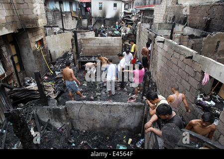 Mandaluyong City, Philippines. 3 juillet, 2014. Résidents comptent pour des matériaux réutilisables après un incendie a frappé une zone résidentielle à Mandaluyong City, Philippines, le 3 juillet 2014. L'incendie a laissé plus de 100 personnes sans-abri et une fille est morte dans l'accident. Credit : Rouelle Umali/Xinhua/Alamy Live News Banque D'Images