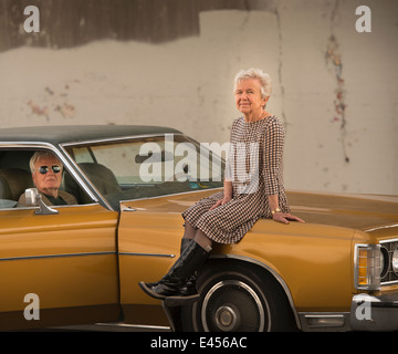 Portrait of senior woman cool sur capot de voiture classique maris Banque D'Images