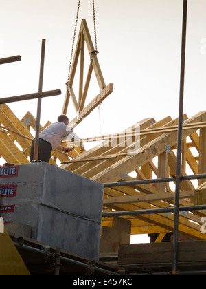 L bâtiment maison, la construction de toit, des fermes de toit en position de levage avec grue Banque D'Images