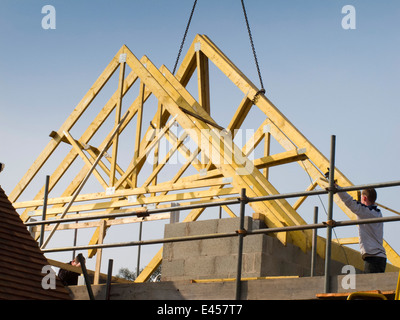 L bâtiment maison, la construction de toit, des fermes de toit en position de levage avec grue Banque D'Images