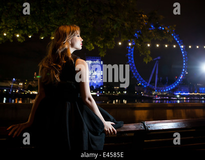 Young woman gazing at London Eye de nuit, London, UK Banque D'Images