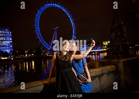 Deux jeunes amies taking self portrait at night, London, UK Banque D'Images