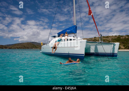 Plongée l'homme au large de la proue d'un Sunsail Lagoon 410 ancrée dans les IVB, dans l'eau près d'un couple sur un li-lo. Avril 2006, le modèle et les biens libérés. Banque D'Images