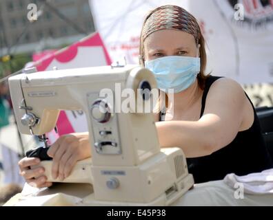 Berlin, Allemagne. 06Th Juillet, 2014. Une jeune femme pose avec un maching couture et un signe à lire 'fast fashion tue" lors de l'ouverture d'un magasin Primark à Alexanderplatz à Berlin, Allemagne, 03 juillet 2014. Les gens protestent contre les mauvaises conditions de travail dans lesquelles les vêtements sont fabriqués. Photo : BRITTA PEDERSEN/dpa/Alamy Live News Banque D'Images