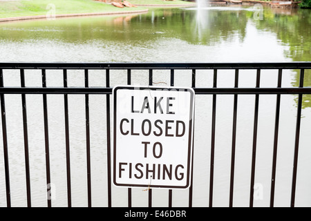 Un signe d'informer Lake Fermé à la pêche est affiché sur une clôture de fer près d'un petit lac dans un parc public à Oklahoma City, Oklahoma. Banque D'Images