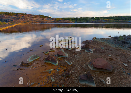 Les roches et le sol, tourner et Rusty intense couleurs rouge comme un bassin de résidus partiellement sèche en Sudbury près de la vallée d'exploitation minière. Banque D'Images