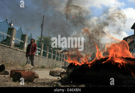 Srinagar, au Cachemire. 4 juillet, 2014. Les musulmans du Cachemire à pied passé brûler des pneus au cours d'une grève spontanée à Srinagar Cachemire indien sur juillet 4,2014 . Les groupes séparatistes opposés à la règle indienne a annoncé une grève pour protester contre la visite du Premier Ministre du pays Narendra Modi . Modi est à sa première visite officielle dans la région himalayenne contestée .il inaugure une ligne de chemin de fer et une centrale, et également vérifier la sécurité et le développement Crédit : Shafat/Pacific Press/Alamy Live News Banque D'Images