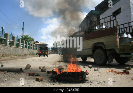 Srinagar, au Cachemire. 4 juillet, 2014. Les musulmans du Cachemire à pied passé brûler des pneus au cours d'une grève spontanée à Srinagar Cachemire indien sur juillet 4,2014 . Les groupes séparatistes opposés à la règle indienne a annoncé une grève pour protester contre la visite du Premier Ministre du pays Narendra Modi . Modi est à sa première visite officielle dans la région himalayenne contestée .il inaugure une ligne de chemin de fer et une centrale, et également vérifier la sécurité et le développement Crédit : Shafat/Pacific Press/Alamy Live News Banque D'Images