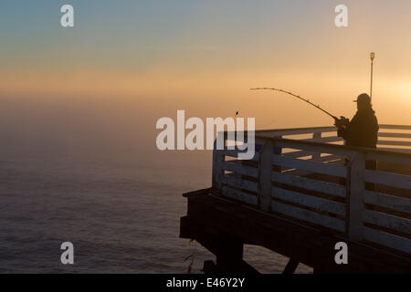 Man fishing sur Crystal Pier, un quai public et l'hôtel, en février 2014. La fin d'après-midi est l'éclairage d'un banc de brouillard. Banque D'Images