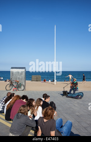 Les gens écoutent de musicien ambulant qui joue de la guitare sur la promenade de la Barceloneta à Barcelone, Catalogne, Espagne. Banque D'Images