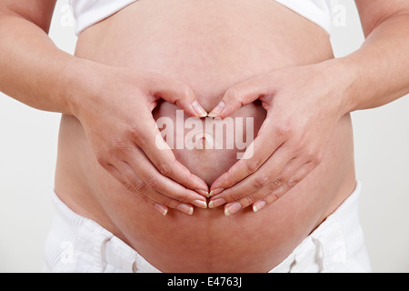 Femme enceinte avec mains formant forme de coeur Banque D'Images