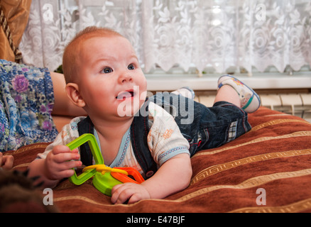 Cute little baby lying on bed et jouer avec des jouets Banque D'Images