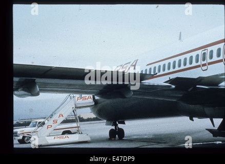 Cette image montre un agent de bord de Pacific Southwest Airlines (PSA), connue pour son rôle dans le développement du transport aérien à bas prix en Californie. L'hôtesse de l'air est vue dans un uniforme vintage, reflétant le style de l'époque et la contribution de la compagnie aérienne à l'histoire de l'aviation. Banque D'Images