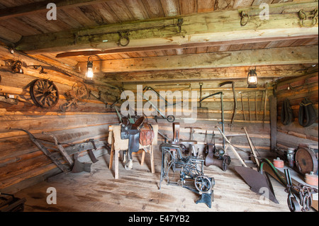 Salle intérieure avec mobilier Matériel agricole log cabin bâtiment maison Heritage Park Museum, Terrace, Colombie-Britannique, Canada. Banque D'Images