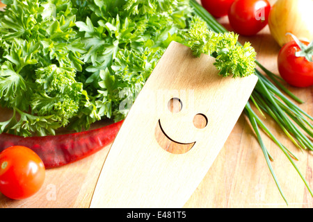 Ustensiles de cuisine en bois sur une planche à découper avec des légumes Banque D'Images