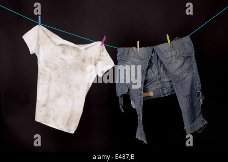 Dirty shirt et pantalon accroché à sécher sur un fond noir Banque D'Images