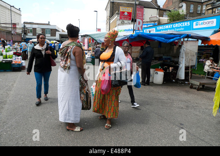 Les femmes afro-britannique shopping dans Ridley Road Market vêtus de la mode africaine ayant une conversation dans l'East End de Londres, Dalston UK KATHY DEWITT Banque D'Images