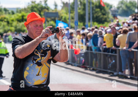 Burley-In-Wharfedale, Yorkshire, Angleterre, Royaume-Uni. 5 juillet 2014 .grande foule de spectateurs se tenir derrière des barrières sur la route de la première étape du Tour de France, alors que 1 l'un homme portant un chapeau trilby orange, est incliné vers l'extérieur, de prendre une photo avec un appareil photo. Crédit : Ian Lamond/Alamy Live News Banque D'Images