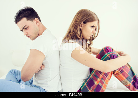 Jeune couple ayant bouleversé les problèmes conjugaux ou un désaccord assis côte à côte dans le lit dos à dos et d'ignorer l'un l'autre. Portrait l'homme et la femme dans l'atmosphère intérieure chambre Banque D'Images