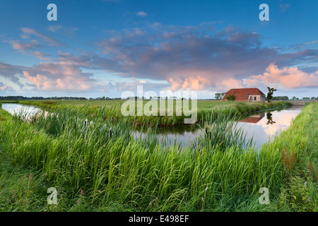 Charmante ferme par la rivière au coucher du soleil, Pays-Bas Banque D'Images