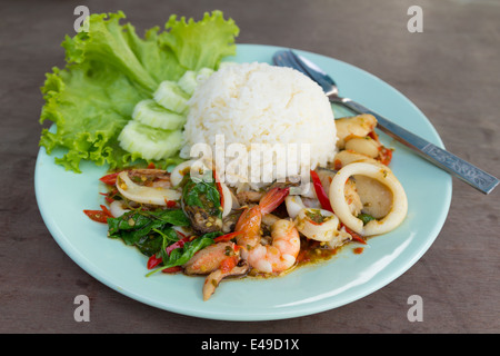 Fruits de mer frits avec des feuilles de basilic sur du riz vapeur. Banque D'Images