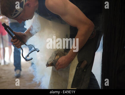 Calgary, Alberta, Canada. 06th juillet 2014. Le farrier s'est fait monter une chaussure de cheval chaude sur le sabot du cheval lorsqu'il participe aux derniers moments de la finale de la compétition des Blacksmitts des Championnats du monde au Stampede de Calgary, dimanche, 6 juillet 2014. Les cinq premiers arrivants se disputent le titre de champion du monde dans cette tradition de longue date au Stampede. Calgary, Alberta, Canada. Crédit : Rosanne Tackaberry/Alamy Live News Banque D'Images