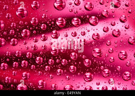 Goutte d'eau sur une surface en verre rouge Banque D'Images