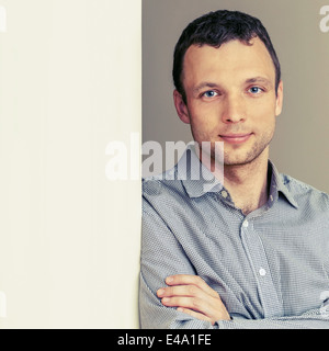 Young Caucasian Man, portrait avec mur gris. Photo couleur Banque D'Images