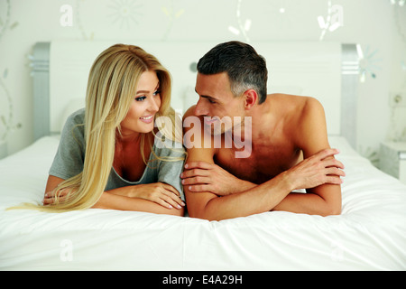 Cheerful couple lying on bed at home Banque D'Images