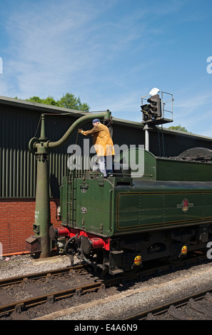 Homme remplissant le train de locomotive à vapeur avec de l'eau en été Pickering Railway Station North Yorkshire Angleterre Royaume-Uni GB Grande-Bretagne Banque D'Images